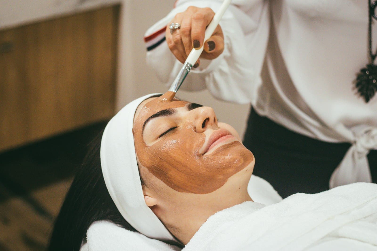 A calming facial mask being brushed onto a client's skin